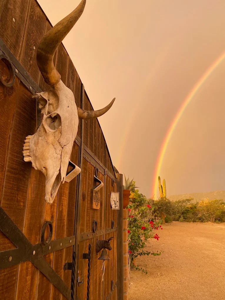 Casa Xolo wooden gate under a double rainbow in El Sargento